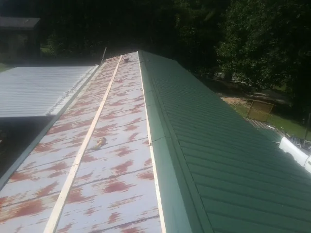 Old rusted panels beside newly installed green metal roofing — Wind Damage Roof Repair by Roofing Brothers in Lovelady