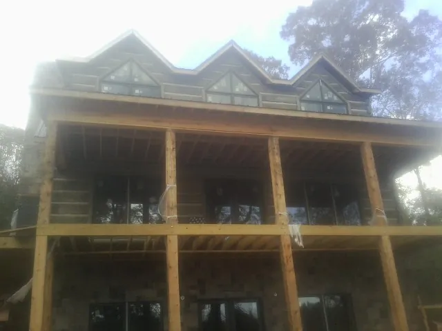 Dormers and porch framing on a large log home under construction — Roof Coating work by our crew in Lovelady