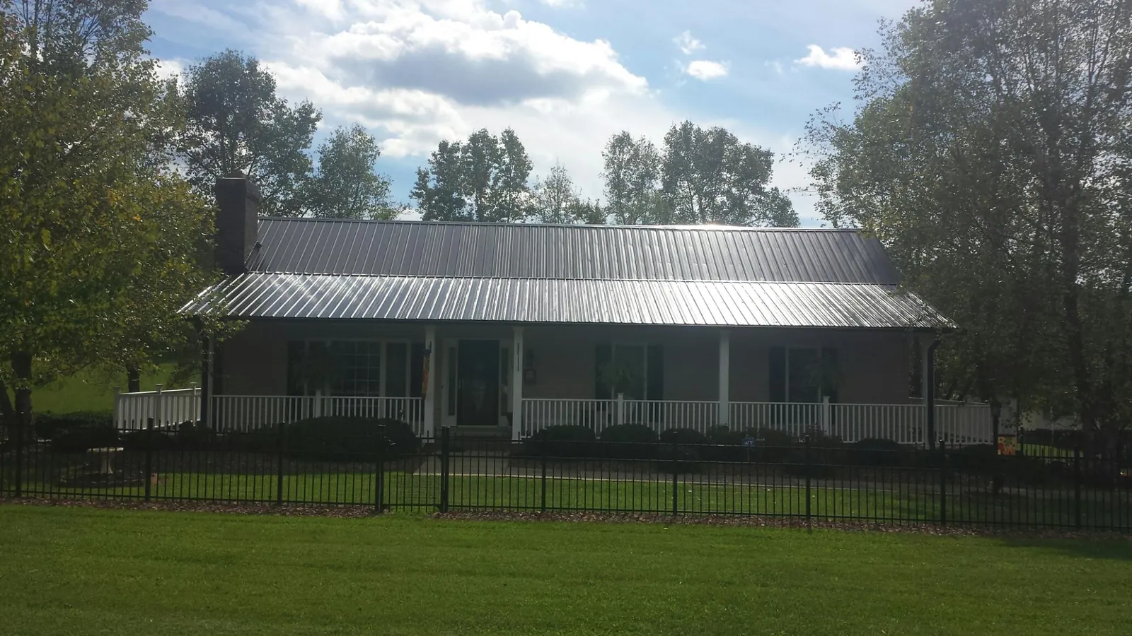 Gray metal roof on a brick ranch with a full width front porch — Gutter Guard Installation work by our crew in Lovelady
