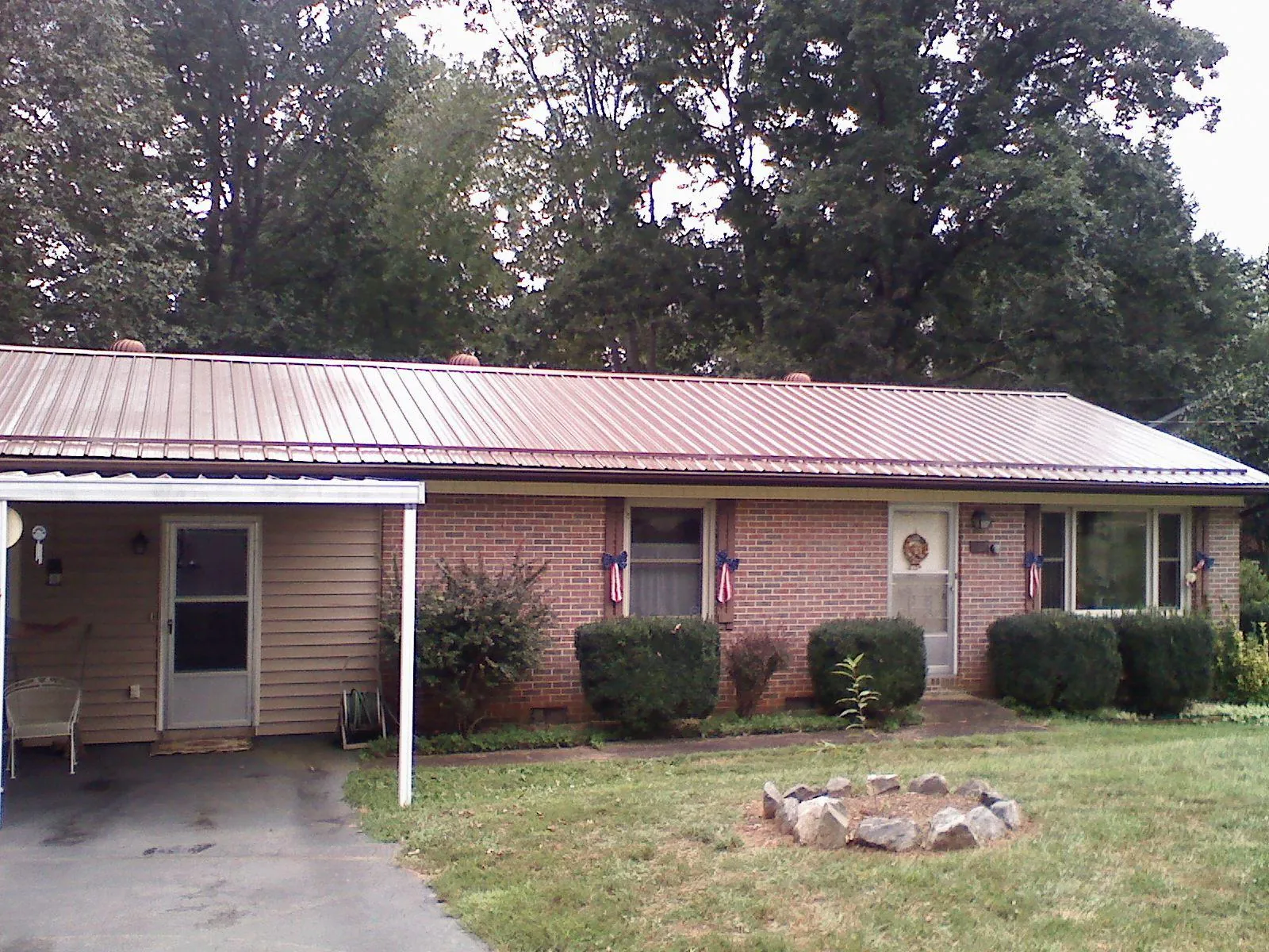 Bronze metal roof and carport on a brick ranch home — Roof Repair work by our crew in Lovelady