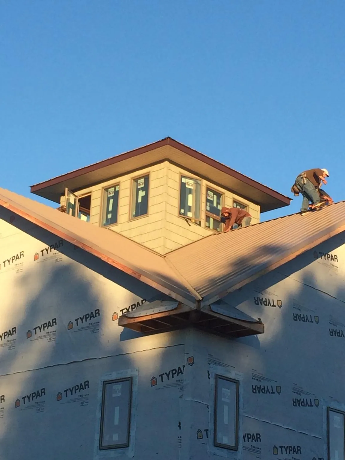 Roofers working around a rooftop cupola on a new metal roof at sunset — Roof Waterproofing in Lovelady by Roofing Brothers
